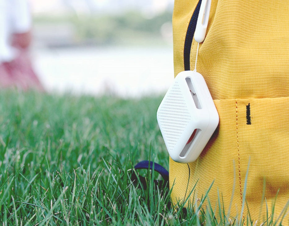 portable mosquito repeller device US travel essential attached to a yellow bag on grass