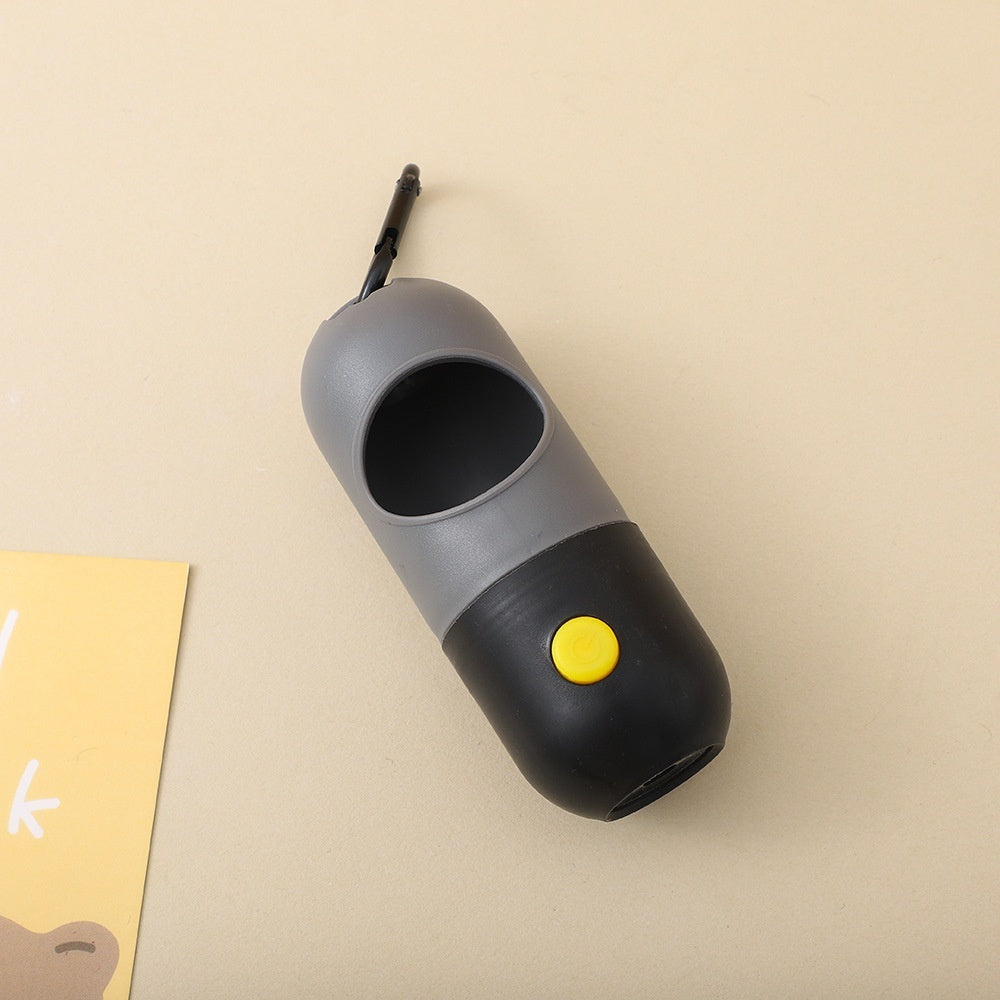 Close up  Gray and black LED pet waste bag dispenser with a yellow button. 