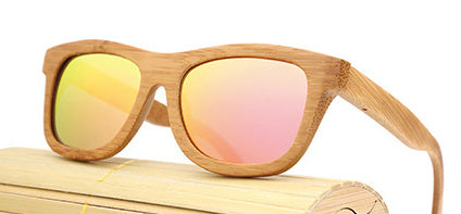 Wooden sunglasses with pink-tinted lenses on a wooden surface