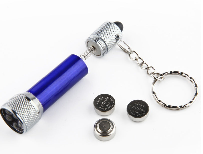 Mini aluminum keychain flashlight outdoors, compact LED torch perfect for emergencies.