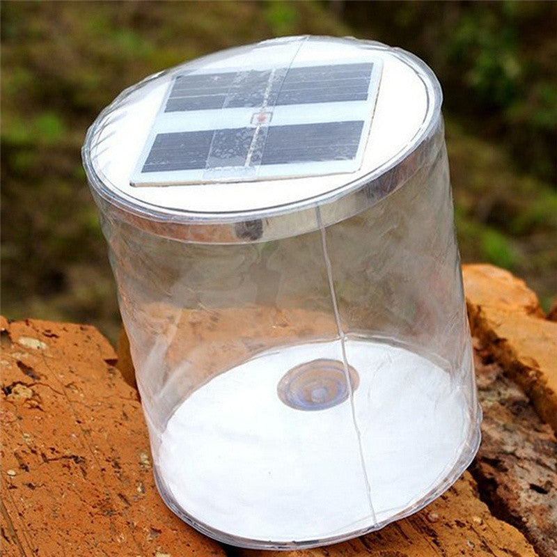 Solar-powered cylindrical light on a wooden surface with a blurred natural background