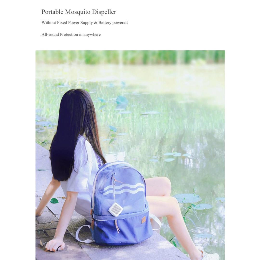 Person sitting by a pond with a blue backpack, with a portable mosquito dispenser.