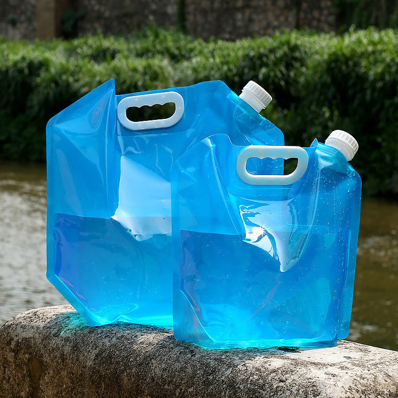 Two blue folding water containers on a stone ledge with greenery in the background