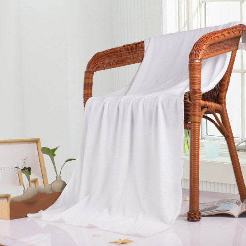 White nano microfiber towel draped over a wicker chair NZ gym gear