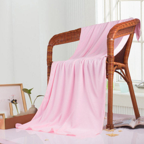 Pink bath towel draped over a wicker chair with a light background