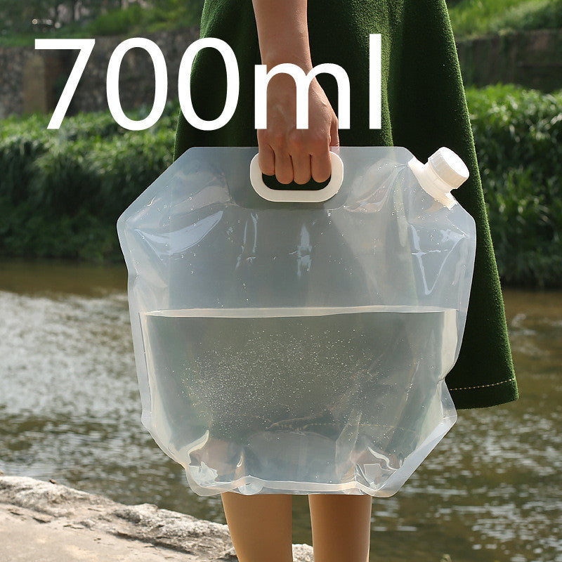 Person holding a transparent water container with a handle, UK outdoors.