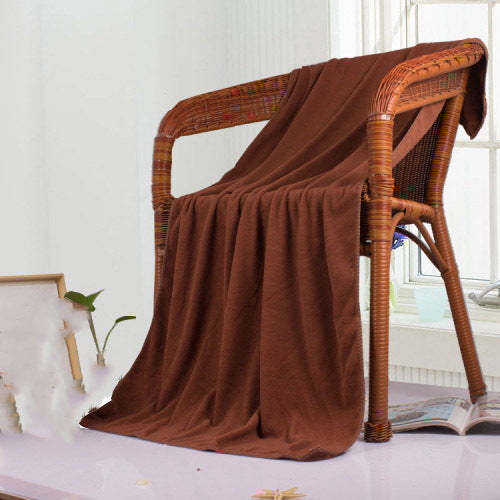 Brown bath towel draped over a wicker chair in a room with a window and plant.