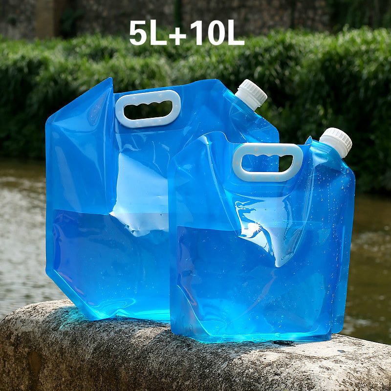 Two blue folding water containers with handles on a stone ledge outdoors.