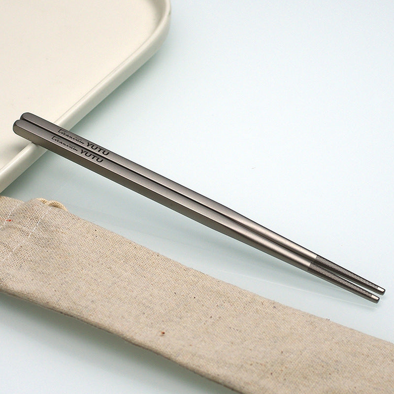 pure titanium chopsticks on a light surface with a beige fabric strip underneath.